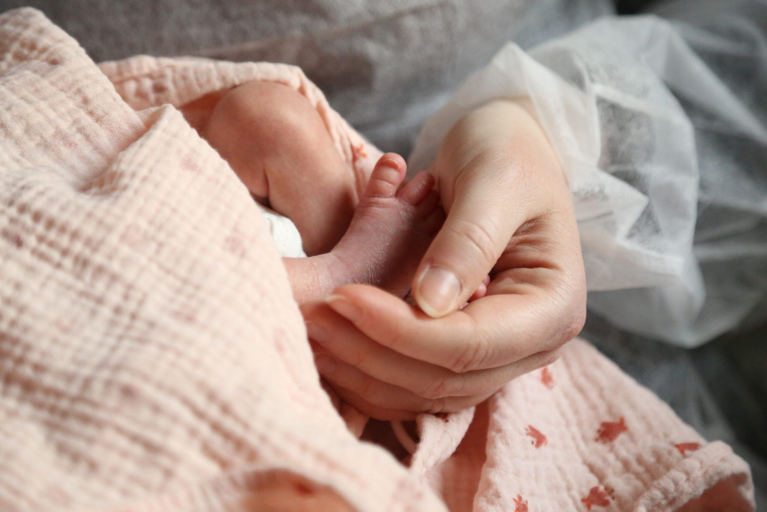 Photo en très gros plan d'une maman tenant le pied de son bébé.