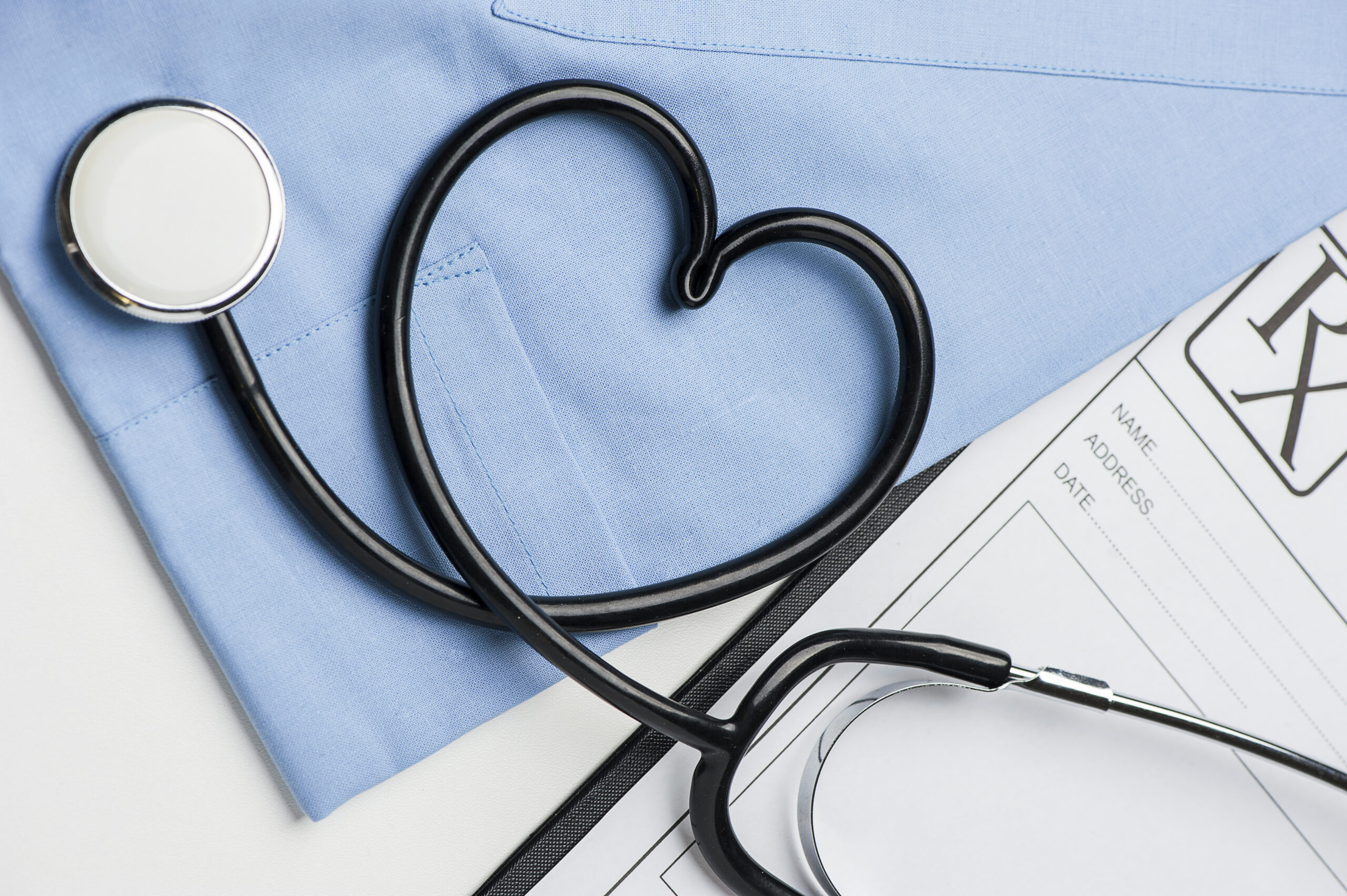 Photo d'un stéthoscope en forme de coeur posé sur une tenue de bloc opératoire