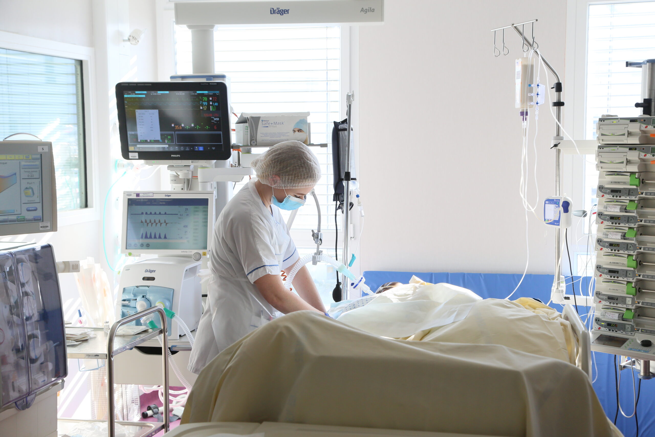 Photo d'une infirmière de bloc au chevet d'un patient alité dans une salle d'opération