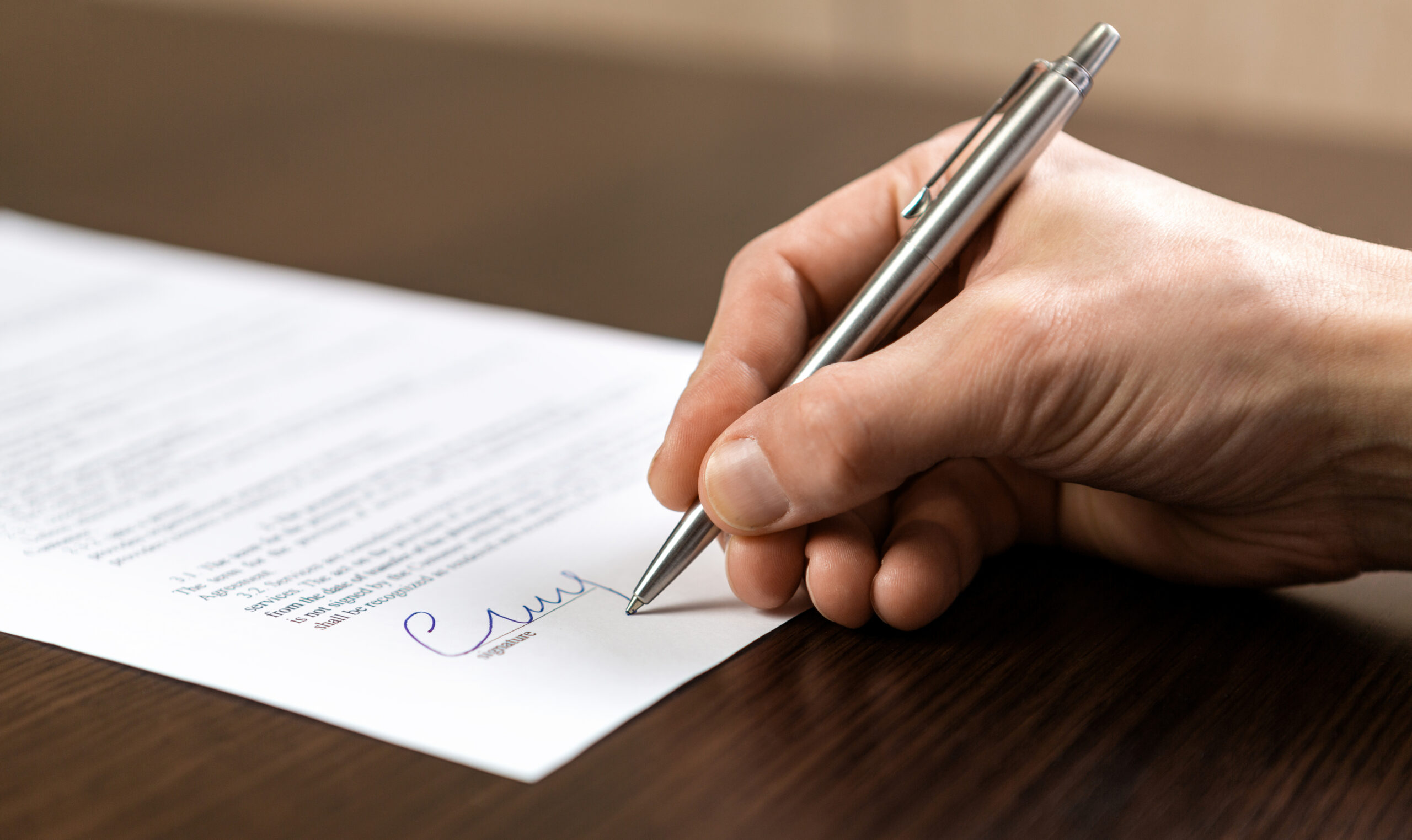 Photo d'une main signant un document avec un stylo bleu